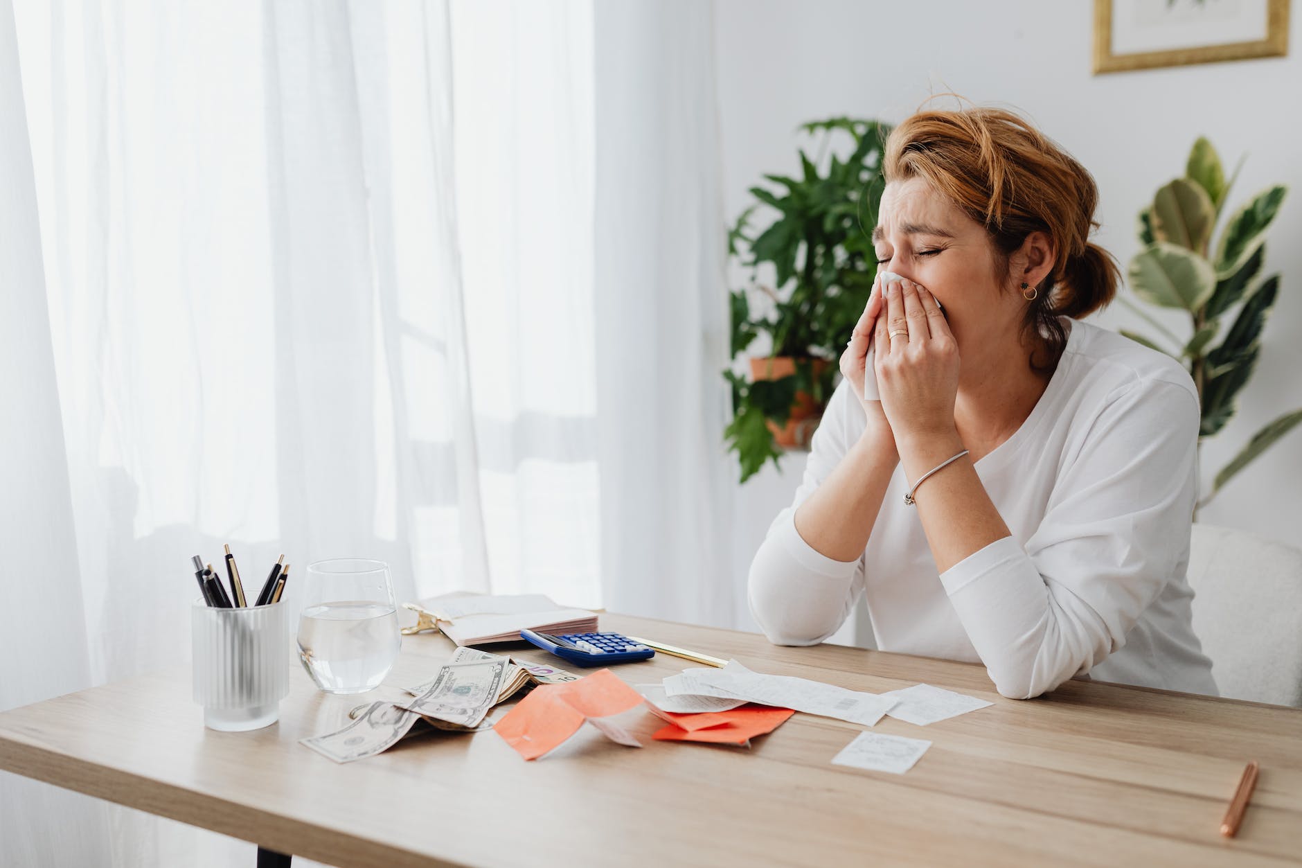 woman crying and dollar bills with receipts on desk